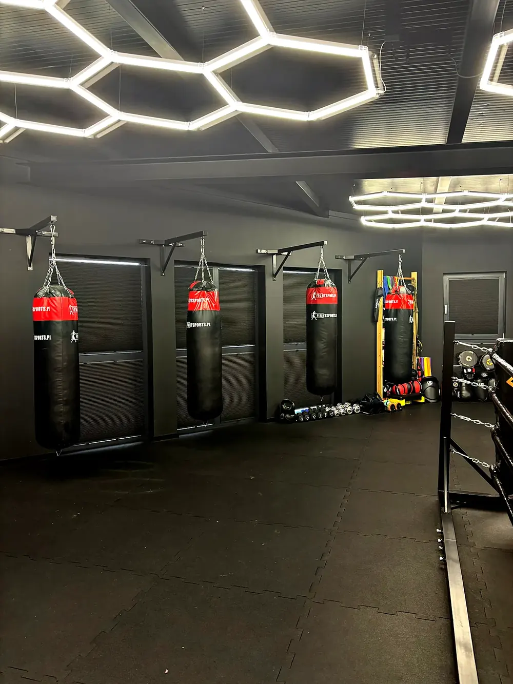 Worki bokserskie w sali PM Boxing Studio pod heksagonalnym oświetleniem
