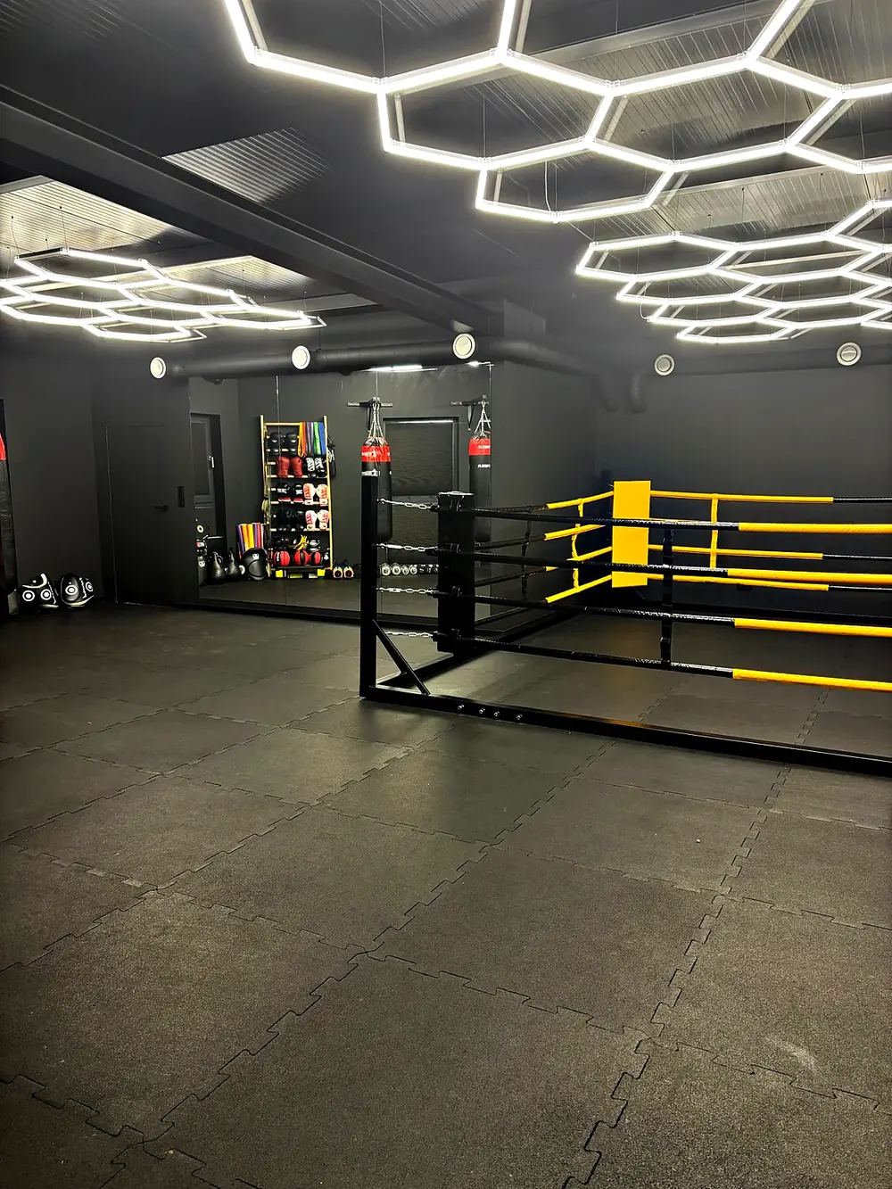Sala PM Boxing Studio z ringiem, workami bokserskimi i heksagonalnym oświetleniem