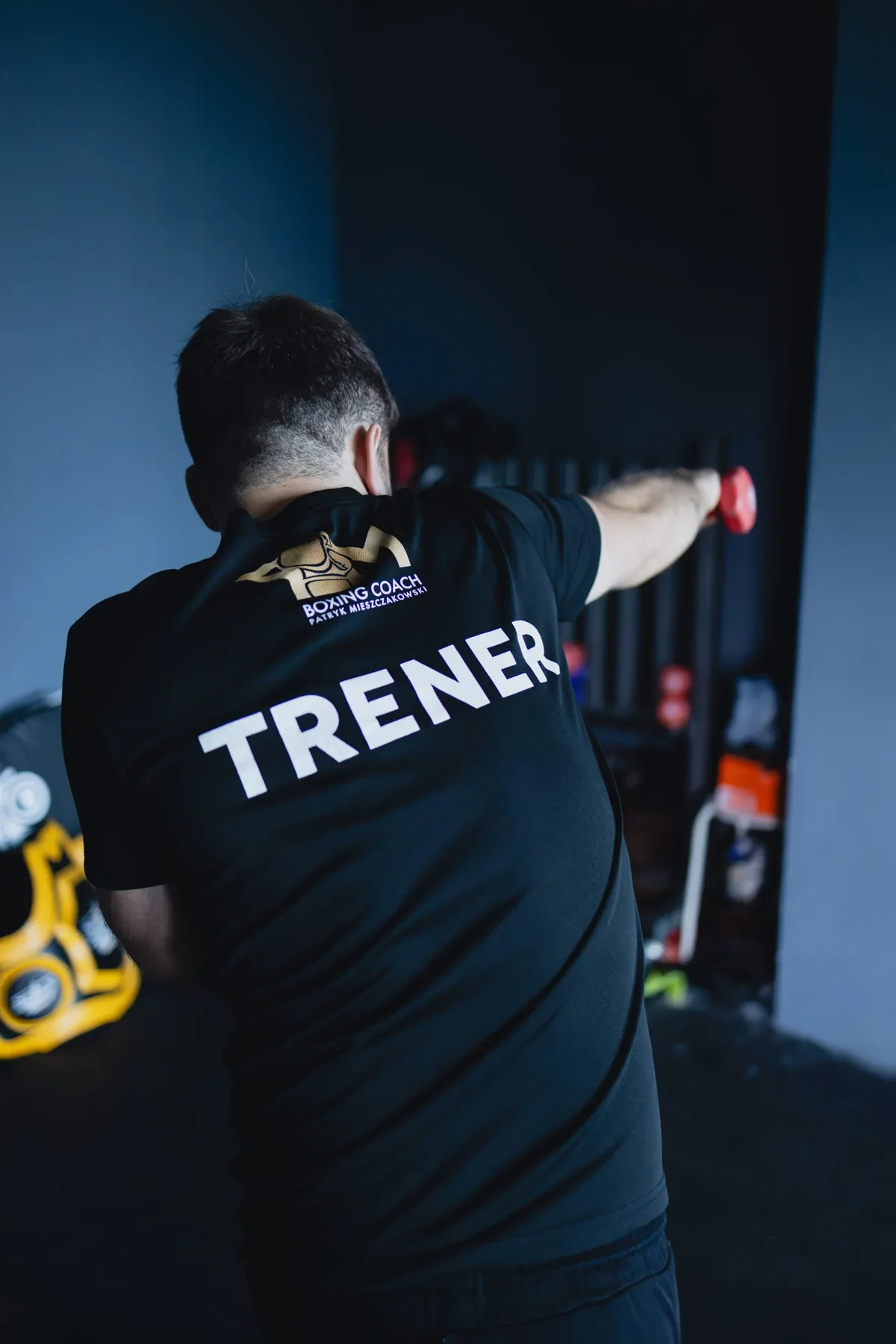 Trener PM Boxing Studio w koszulce z napisem TRENER, wyprowadzający cios w trakcie treningu